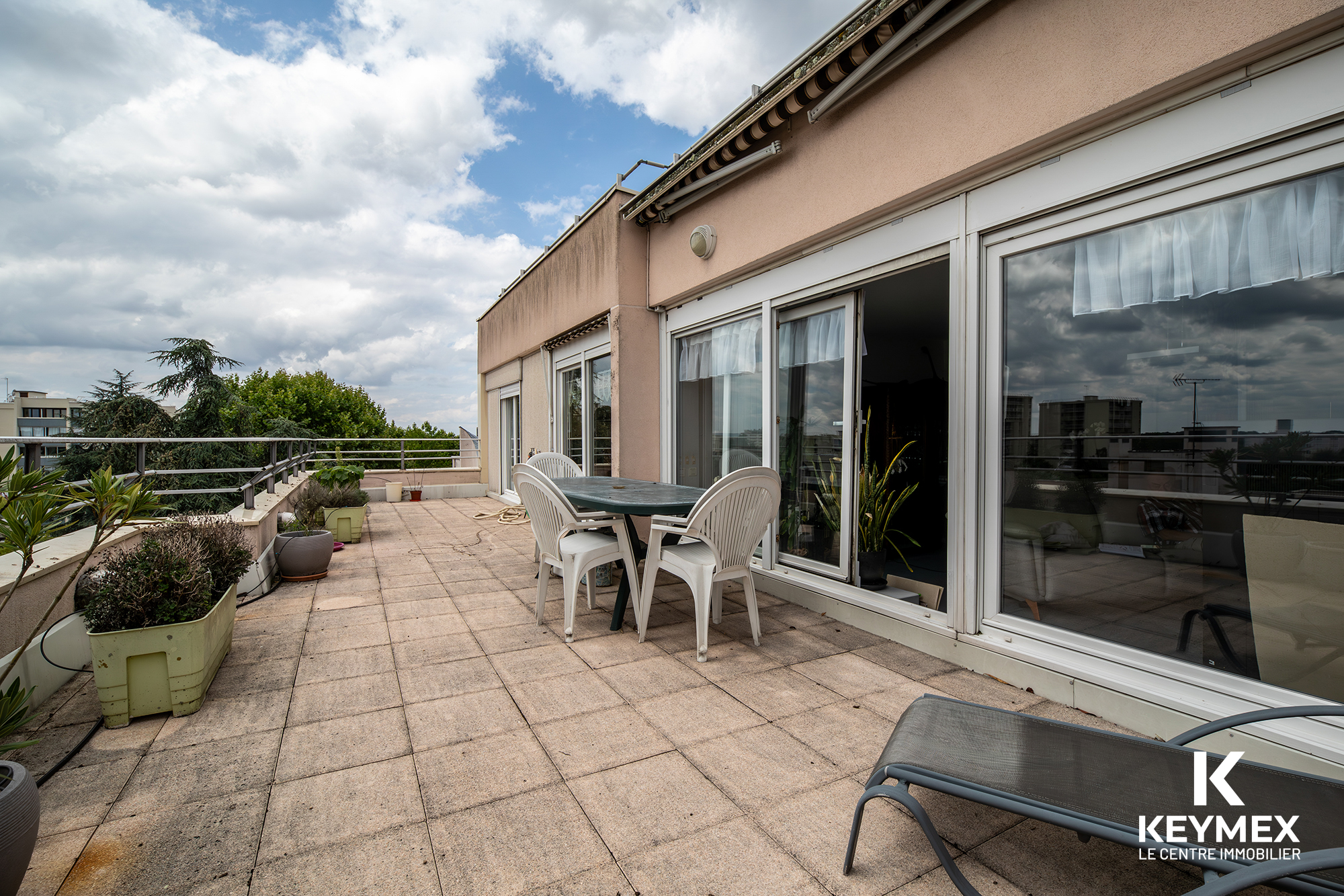 Grande terrasse extérieure avec mobilier de jardin.