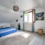 Chambre lumineuse avec lit double et fenêtres ouvertes.