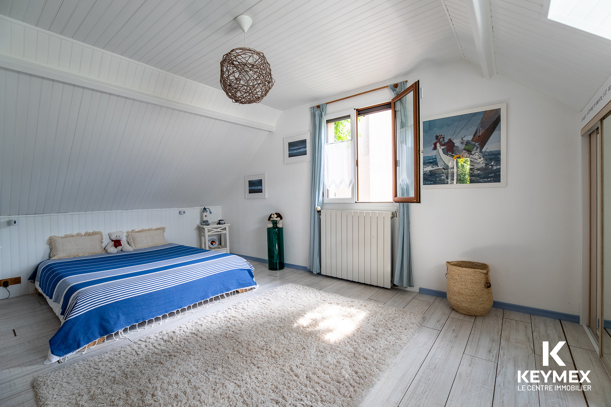 Chambre lumineuse avec lit double et fenêtres ouvertes.