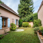 Jardin avec maison aux volets bleus en France.