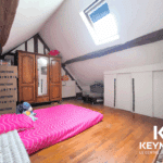 Chambre mansardée avec matelas et armoire en bois.