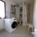 Salle de bain moderne avec douche et machine à laver.