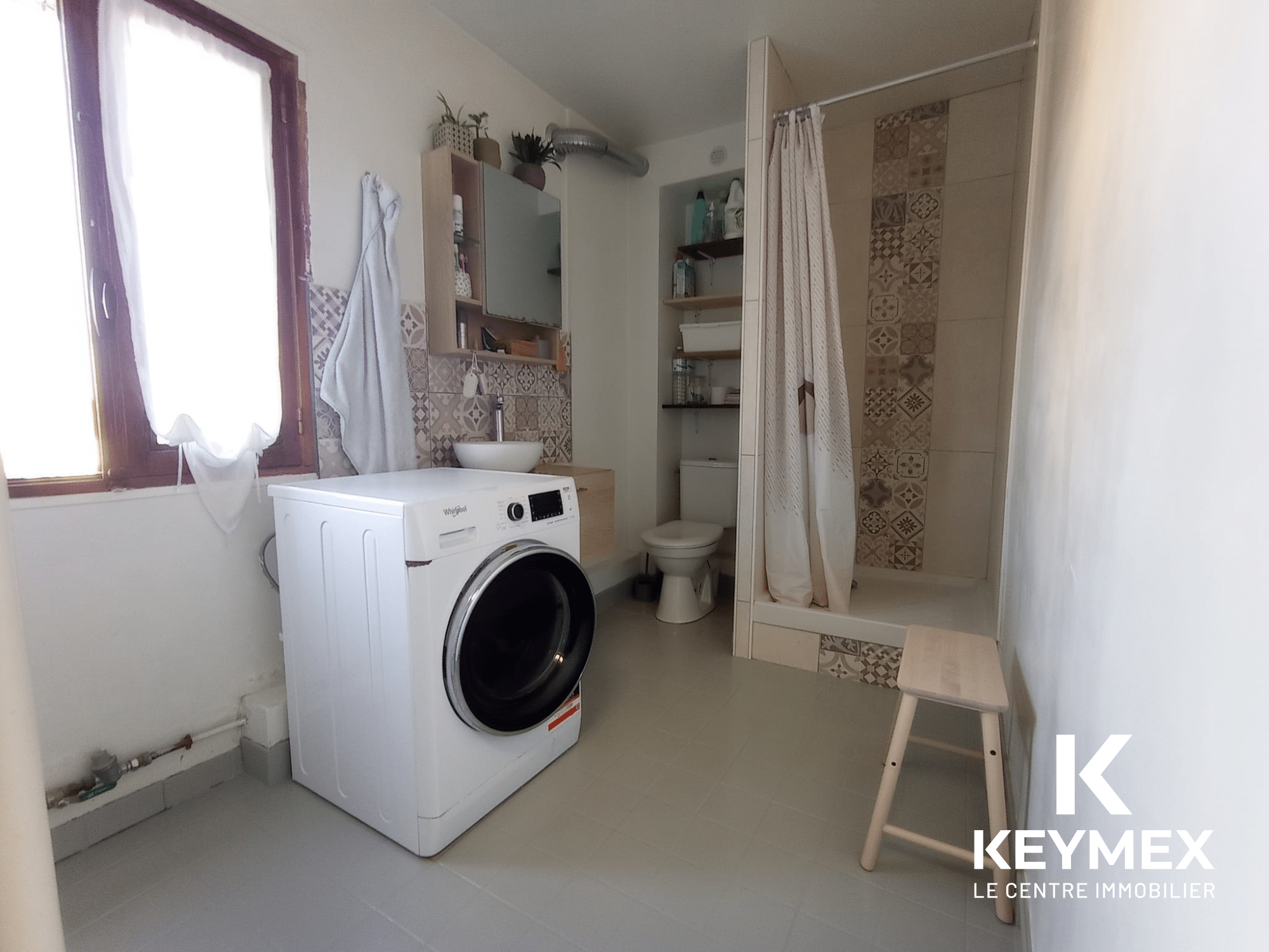 Salle de bain moderne avec douche et machine à laver.