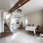 Intérieur cuisine rustique avec table et escalier.