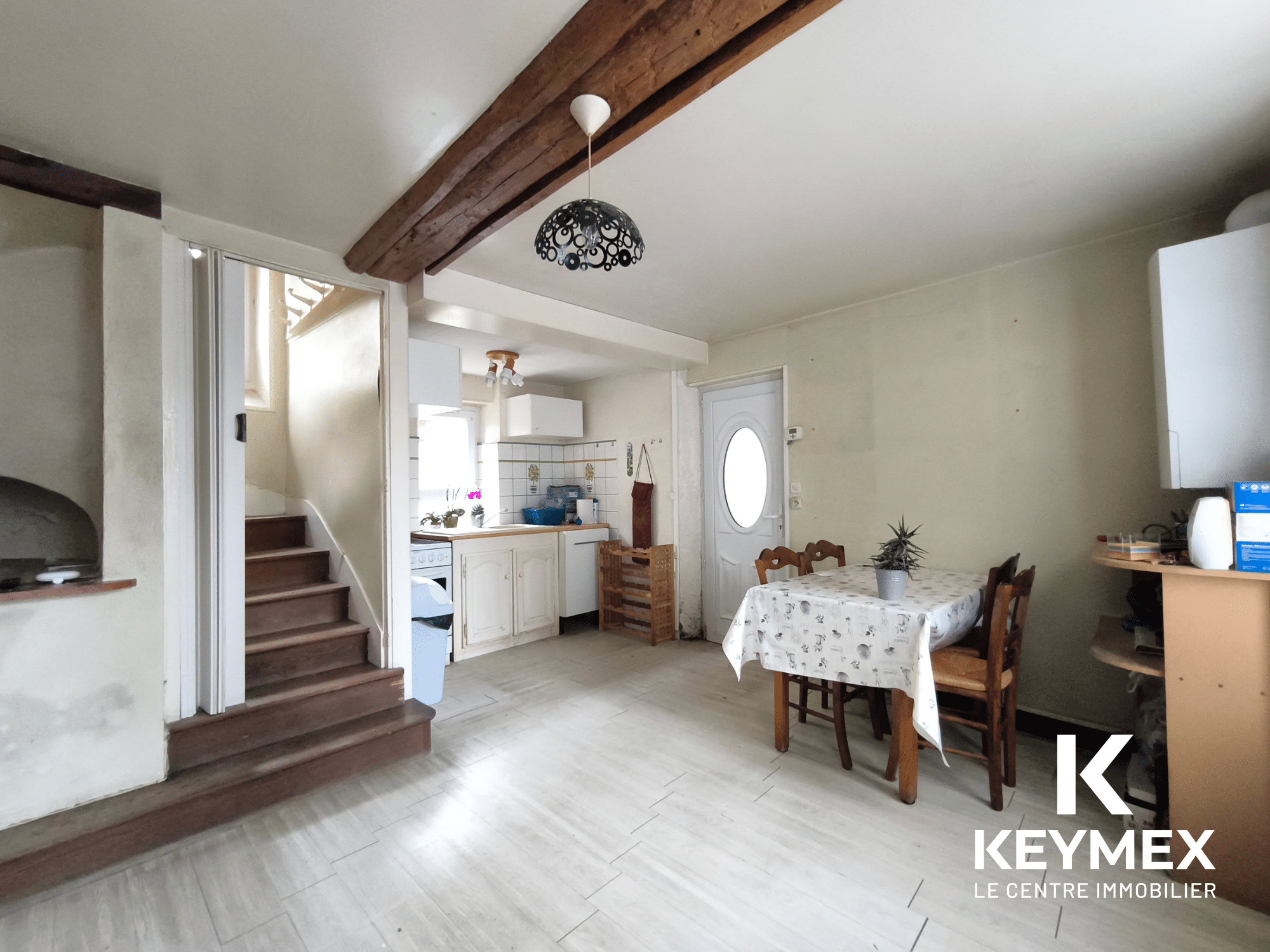 Intérieur cuisine rustique avec table et escalier.