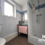 Salle de bain moderne avec douche et lavabo.