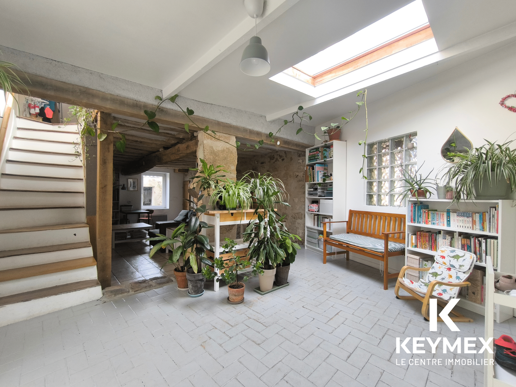 Salon lumineux avec plantes et escaliers modernes.