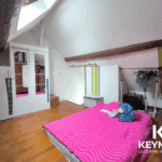 Chambre avec matelas et armoire sous toit mansardé.