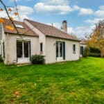 Maison avec jardin en automne, ciel bleu.