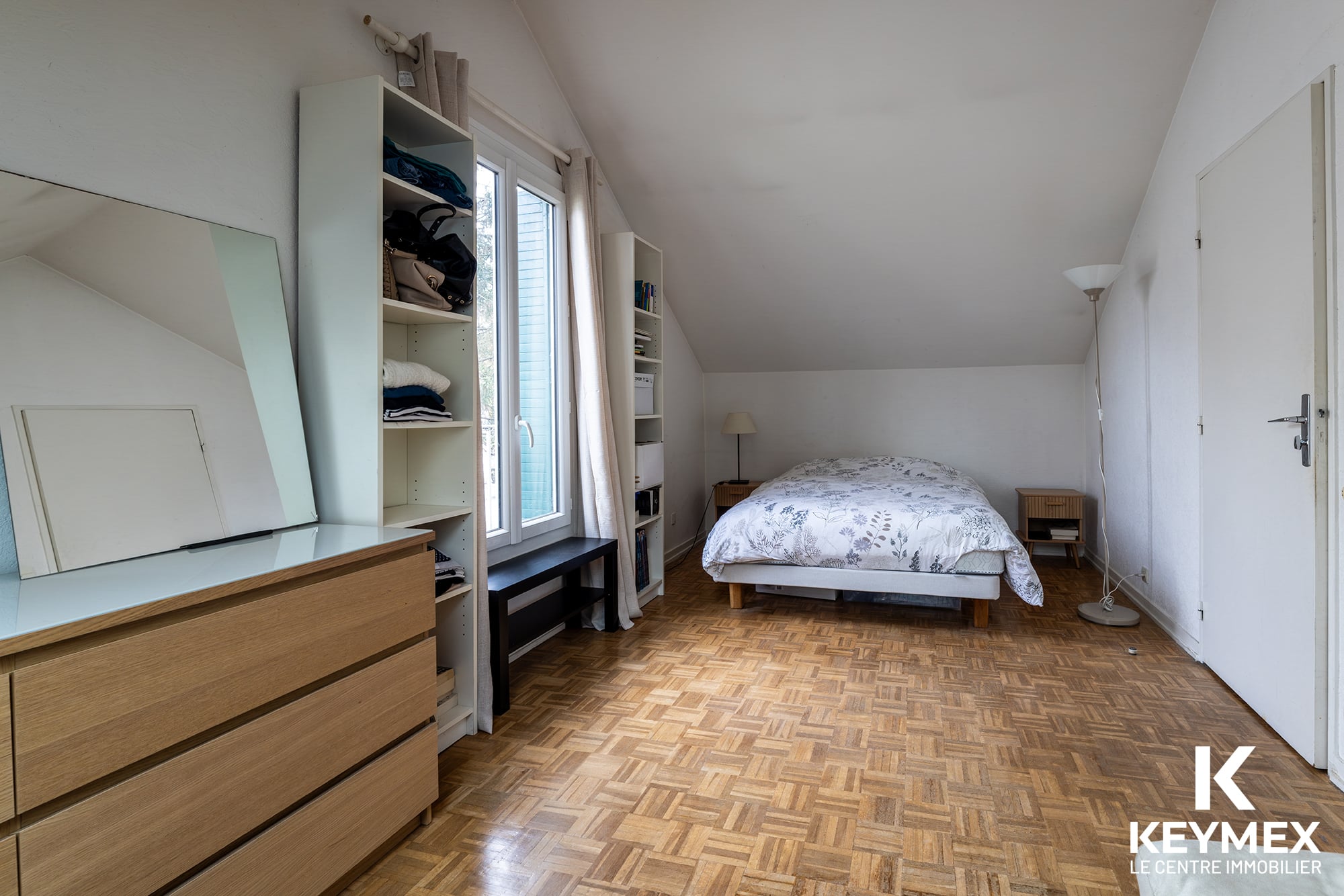 Chambre lumineuse avec parquet et lit confortable.