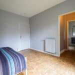 Chambre spacieuse avec parquet et salle de bain.