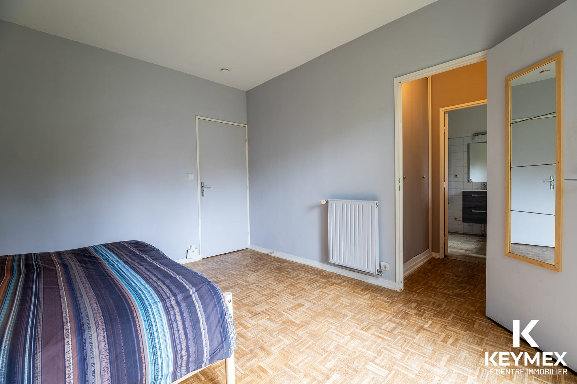 Chambre spacieuse avec parquet et salle de bain.