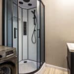 Salle de bain moderne avec douche et lave-linge.