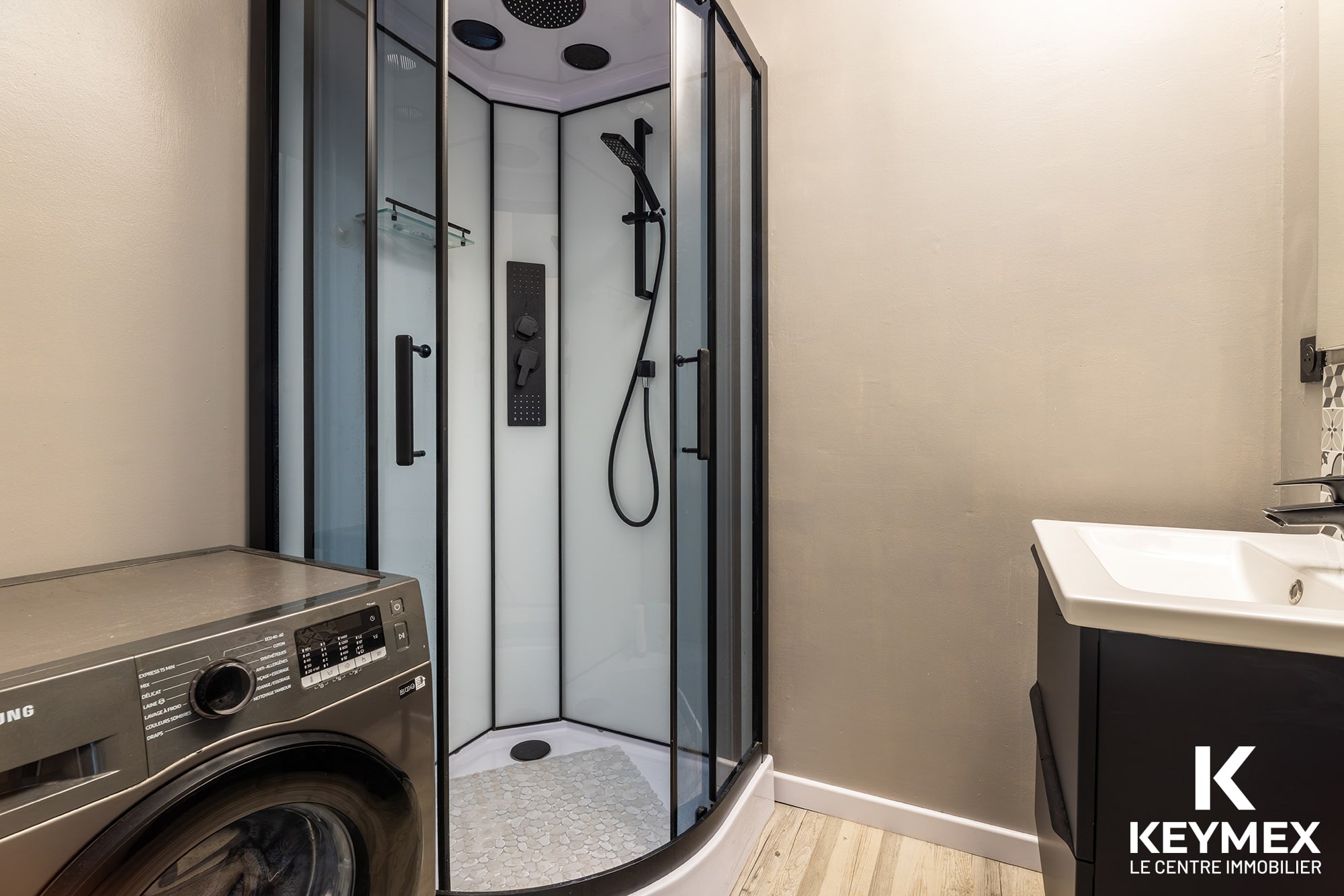 Salle de bain moderne avec douche et lave-linge.