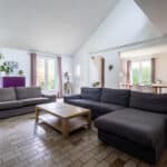 Salon lumineux avec canapés gris et table basse.