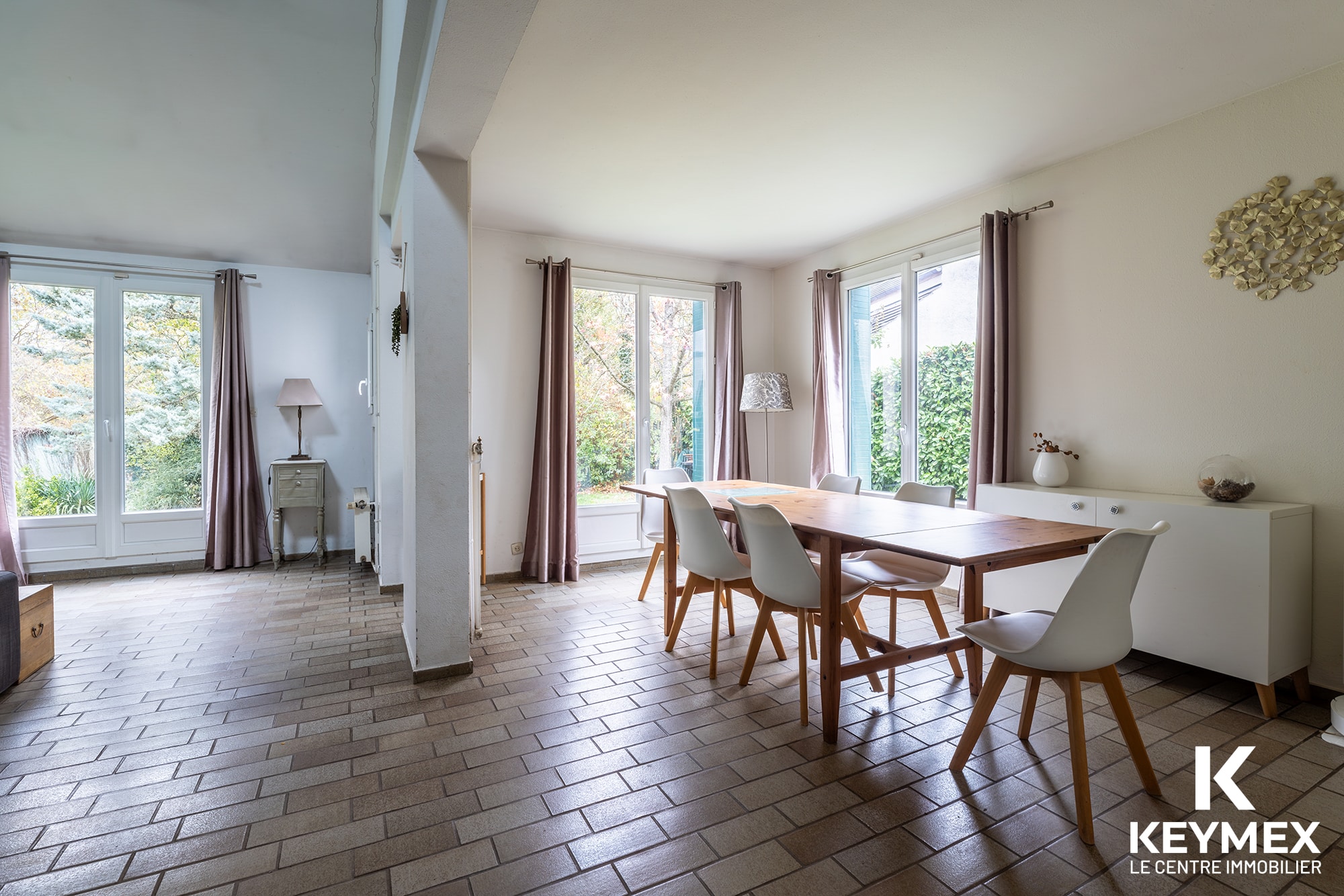 Salle à manger lumineuse avec grandes fenêtres.