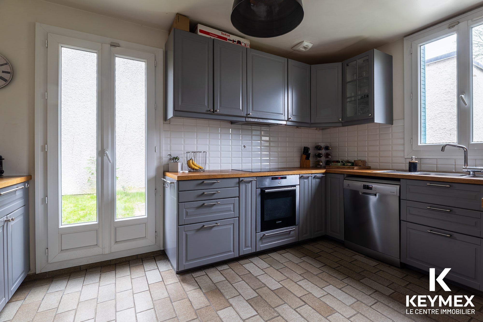 Cuisine moderne avec armoires grises et électroménagers.