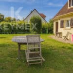 Jardin avec table en bois et maison beige.