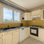 Cuisine moderne avec meubles crème et murs jaunes.