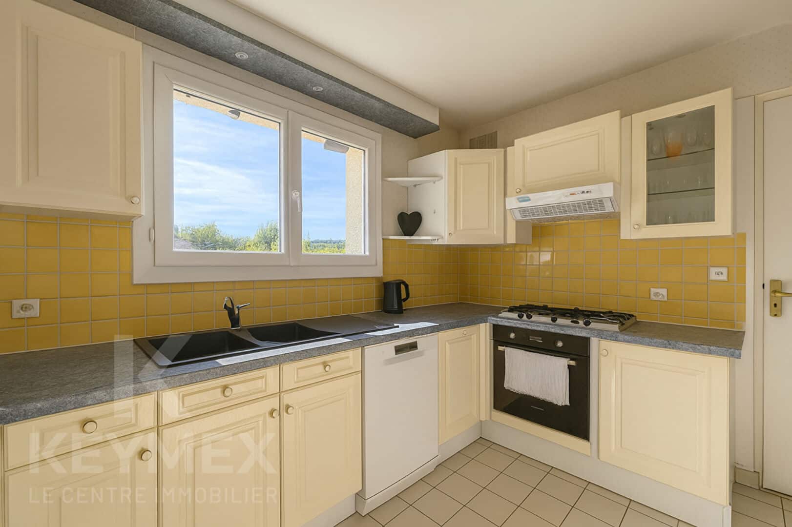 Cuisine moderne avec meubles crème et murs jaunes.