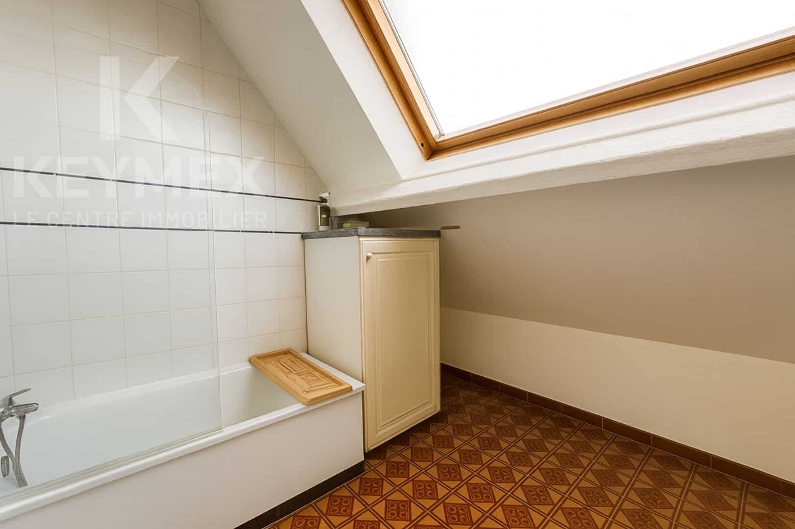 Salle de bain moderne avec baignoire et fenêtre.