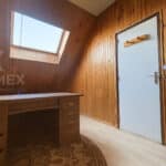 Bureau mansardé avec fenêtre de toit et parquet.