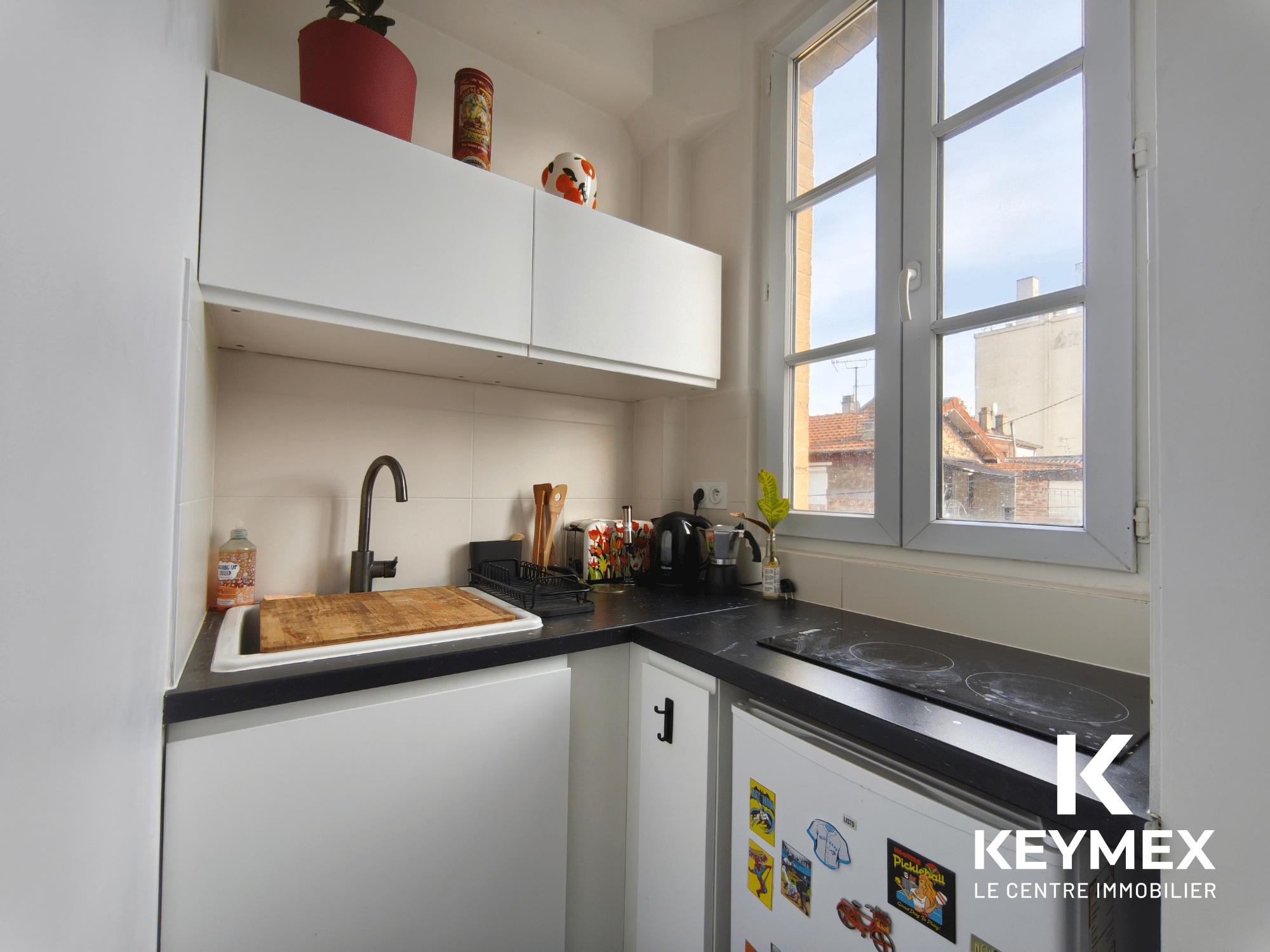 Petite cuisine moderne avec fenêtre et évier.