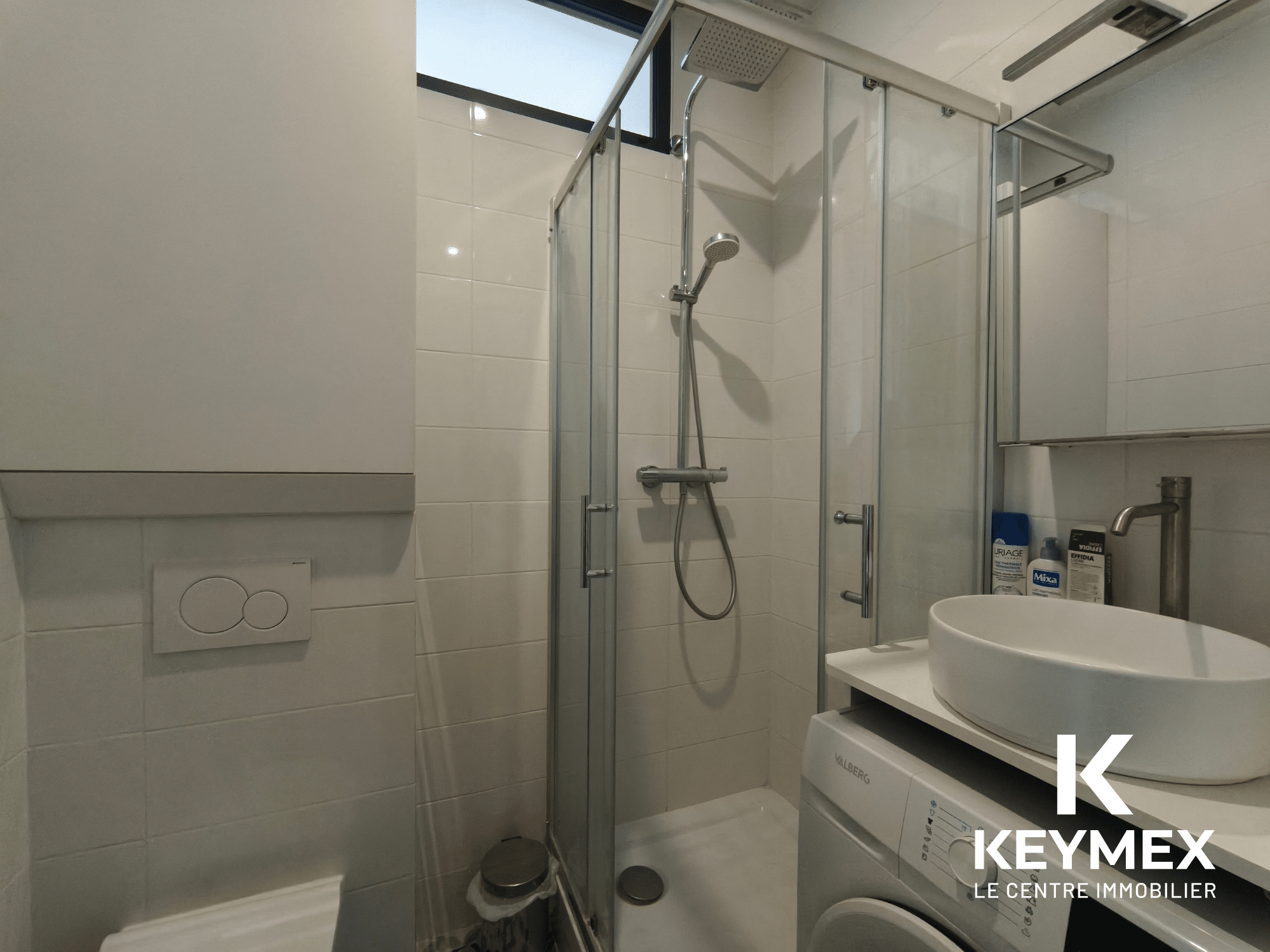 Salle de bain moderne avec douche et lavabo.